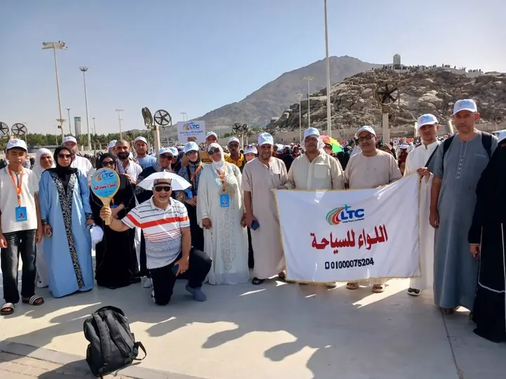مجموعة من عملاء اللواء للسياحة مع لافتة الشركة في عرفات
