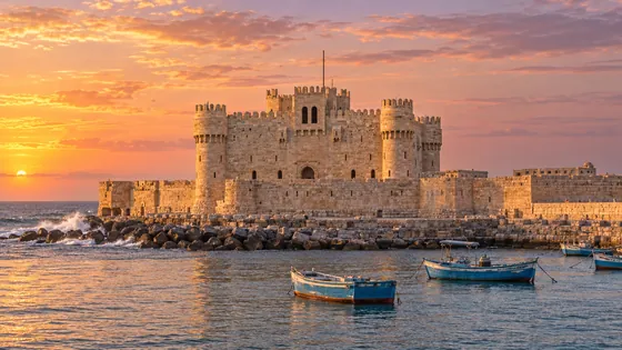 قلعة قايتباي ومراكب الصيد في الميناء الشرقي بالإسكندرية وقت الغروب